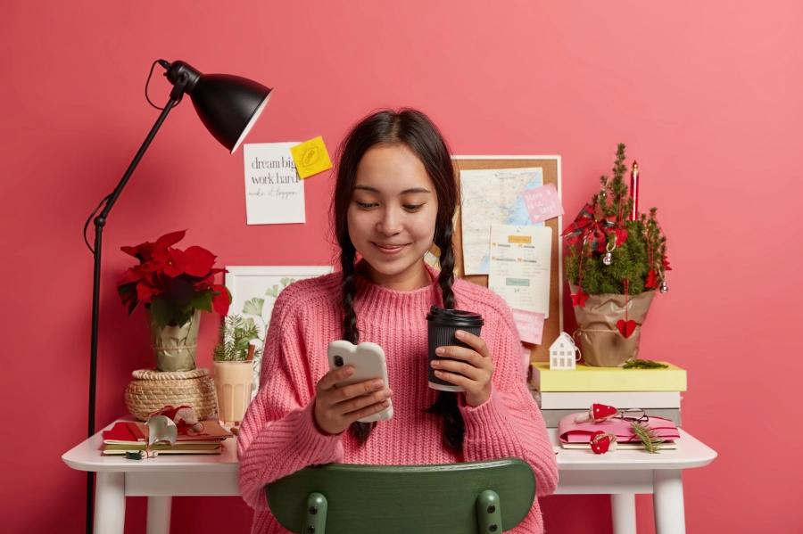 une femme chez elle sourit en étant sur son téléphone