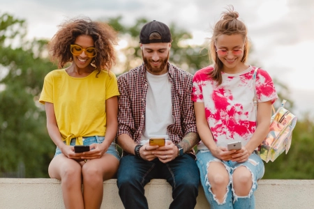 appy-young-company-smiling-friends-sitting-park-a-l-aide-de-smartphones