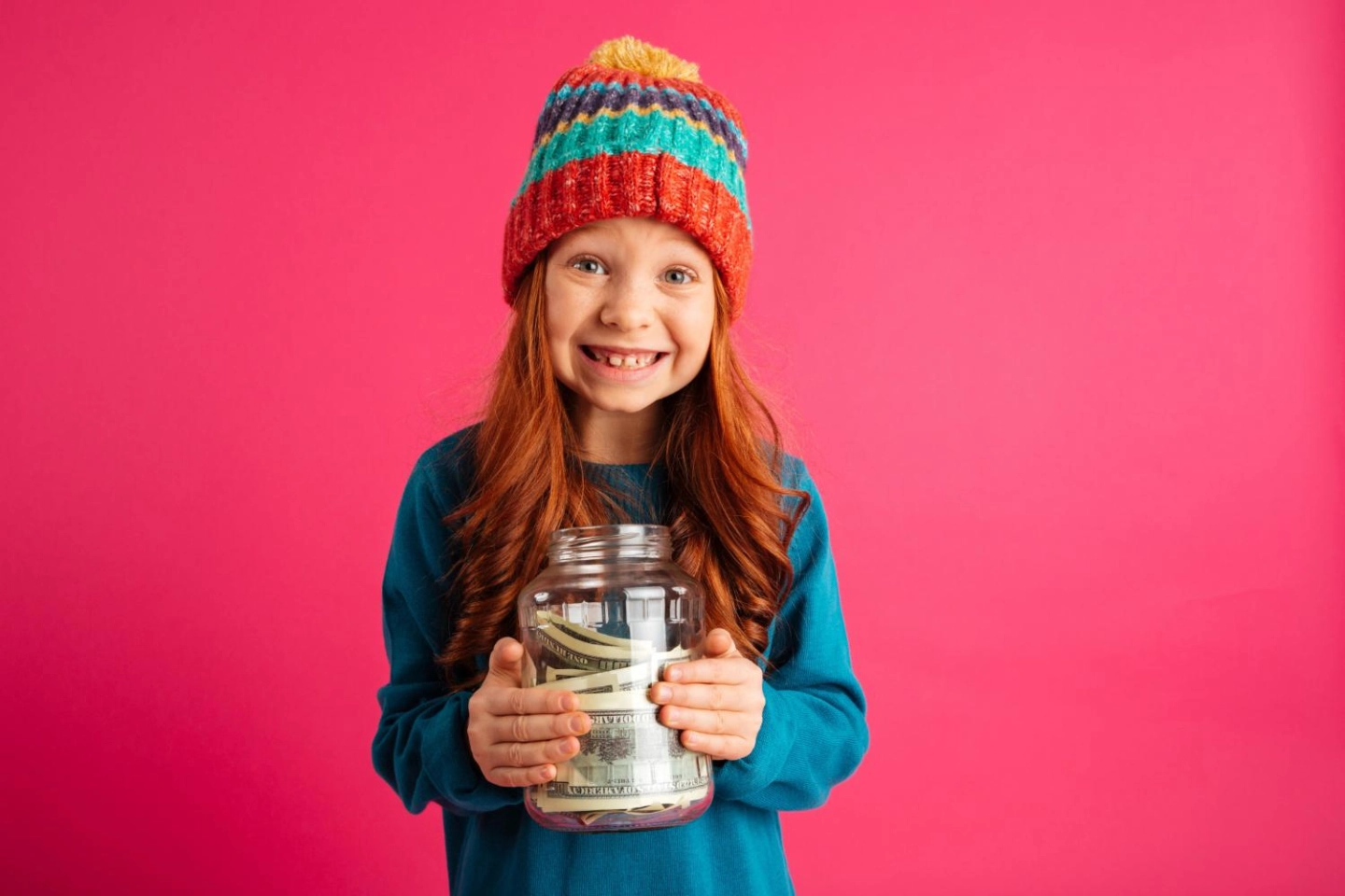 Joyeuse fille tenant une tirelire et souriant à la caméra isolée