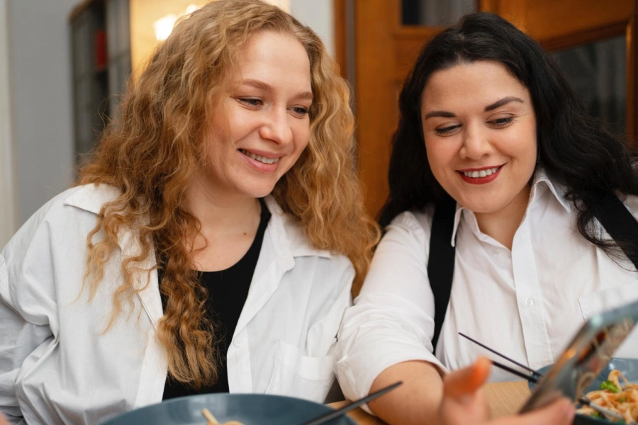 2 AMIES CONSULTENT LEUR TELEPHONE EN SOURIANT